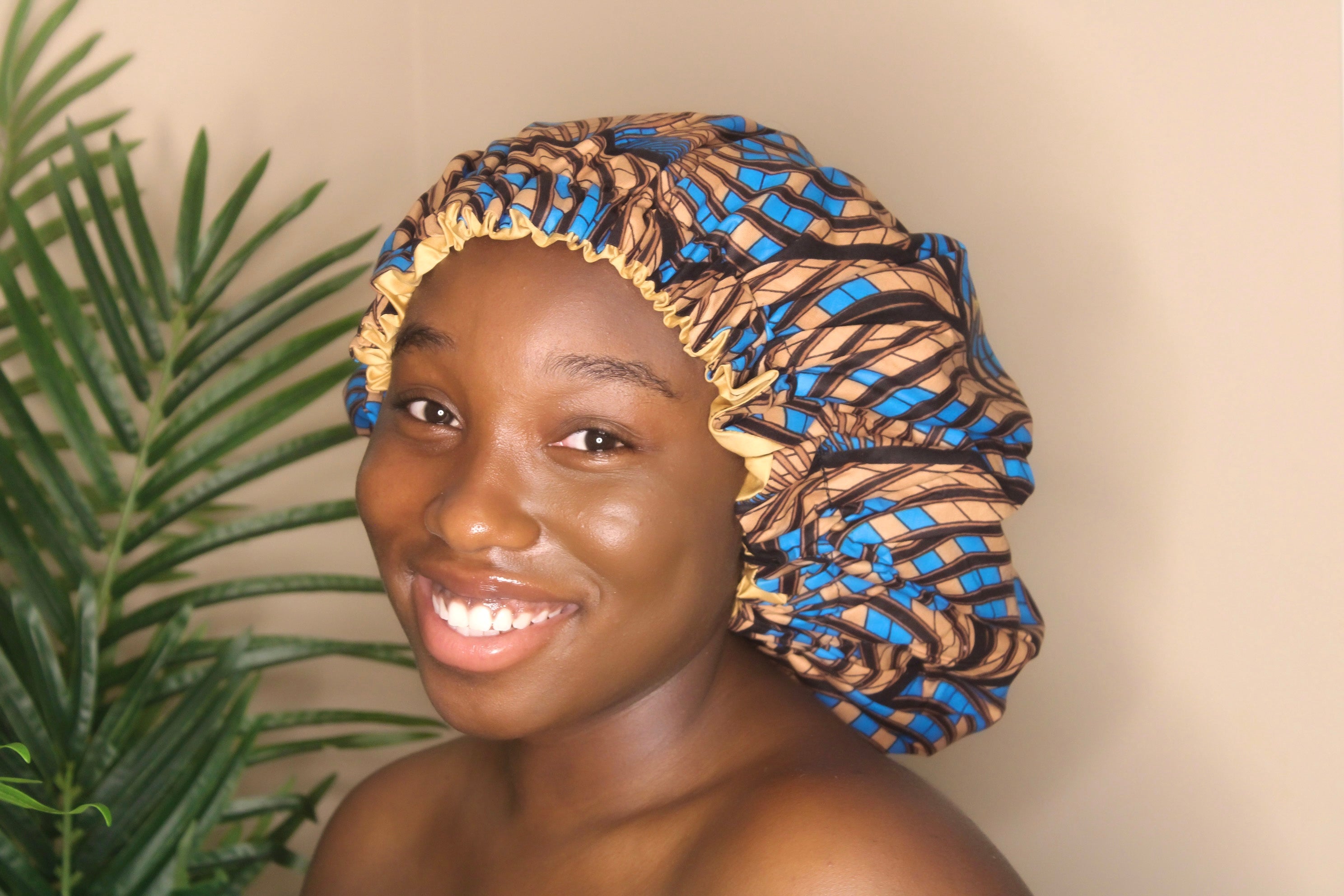 Brown skin model wearing a large satin lined bonnet in color blue. This bonnet is a kente bonnet, african print satin lined, ankara bonnet, hair bonnet